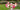 Bouquet of pink and white roses in a silver vase on a wrought iron table outdoors with green lawn behind.