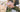 Shoulder and arm of a woman with blush roses in a metal bucket hanging on her elbow and a bouquet of pink roses in her hands. 