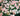 A dense cluster of light pink and white roses with green foliage, filling the entire frame.