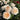 A close-up of peach and cream rose blooms with green foliage in a garden setting, with more flowers blurred in the background.