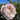 A close-up of a pale pink rose bloom with green leaves and buds against a bright blue sky.