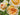 Close-up of pale peach and cream roses with water droplets on their petals, set against soft green foliage.