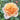 A close-up of a peach and pale pink rose bloom with layered petals, surrounded by green foliage in a garden setting.